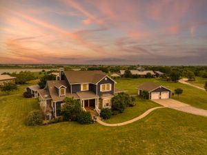 Aerial view of craftsman style home with circular driveway during dramatic sunset.