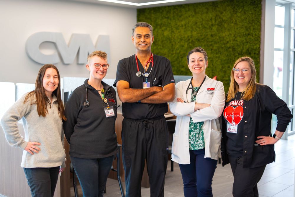 A group of medical professionals pose together in an office with a green accent wall. Quad Cities Photography