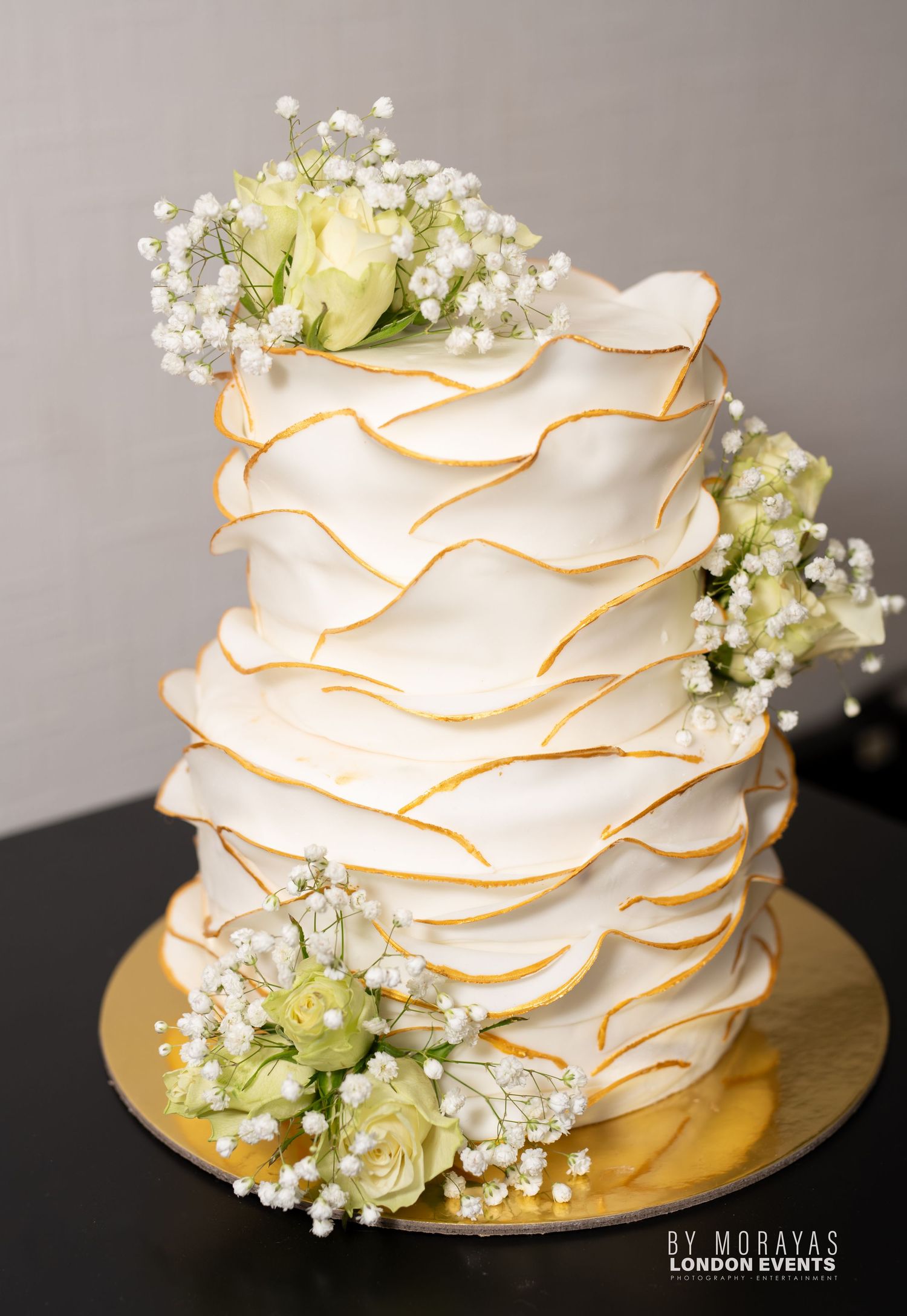 Elegant white wedding cake decorated with delicate ruffles and baby's breath flowers.