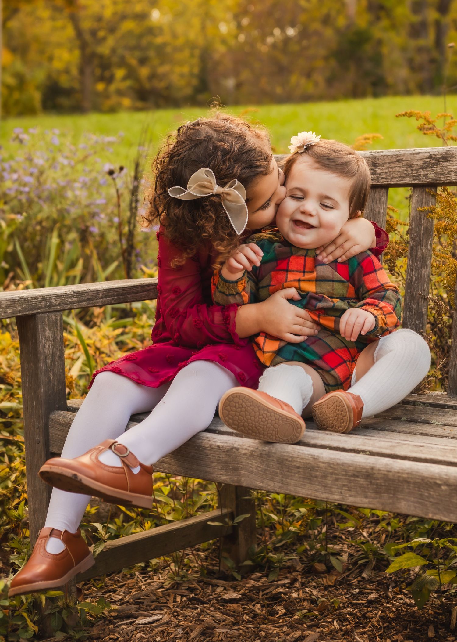 Charlottesville photographer, family, newborn, maternity, baby sisters on a bench kissing for fall session