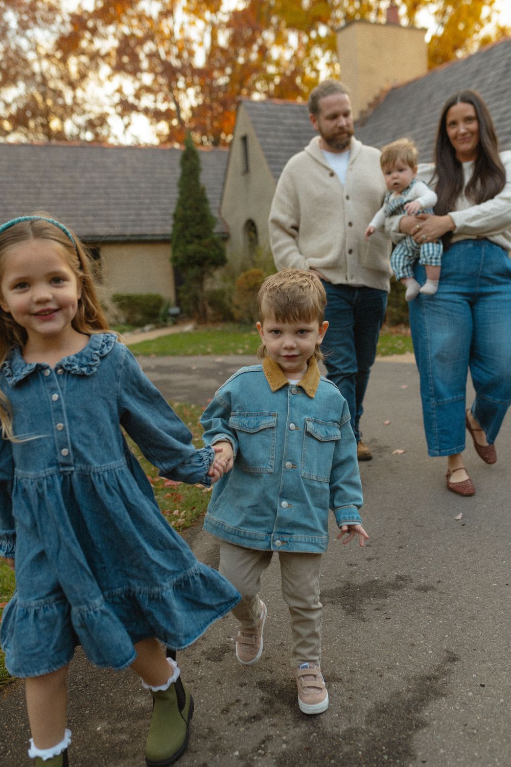 Children playing and running together on a path wearing coordinated denim outfits during an autumn day.