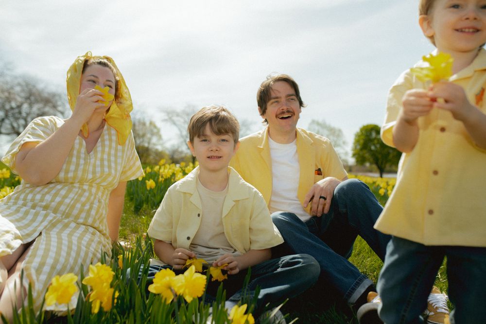 A joyful family moment in a sunny spring meadow filled with blooming yellow daffodils.