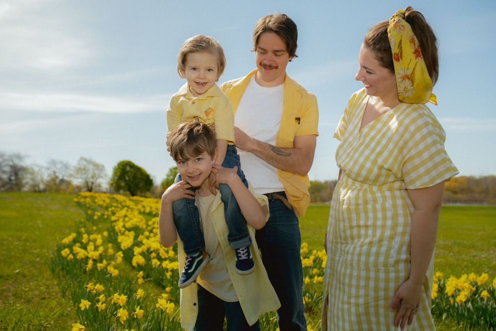 A playful scene of family members enjoying themselves amidst a field of bright yellow daffodils on a sunny day.