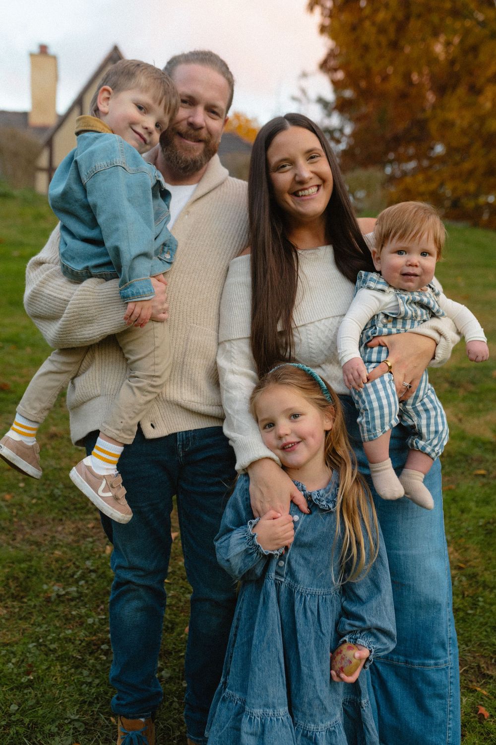 Family portrait series in coordinating denim and cream outfits posing together on an autumn day.