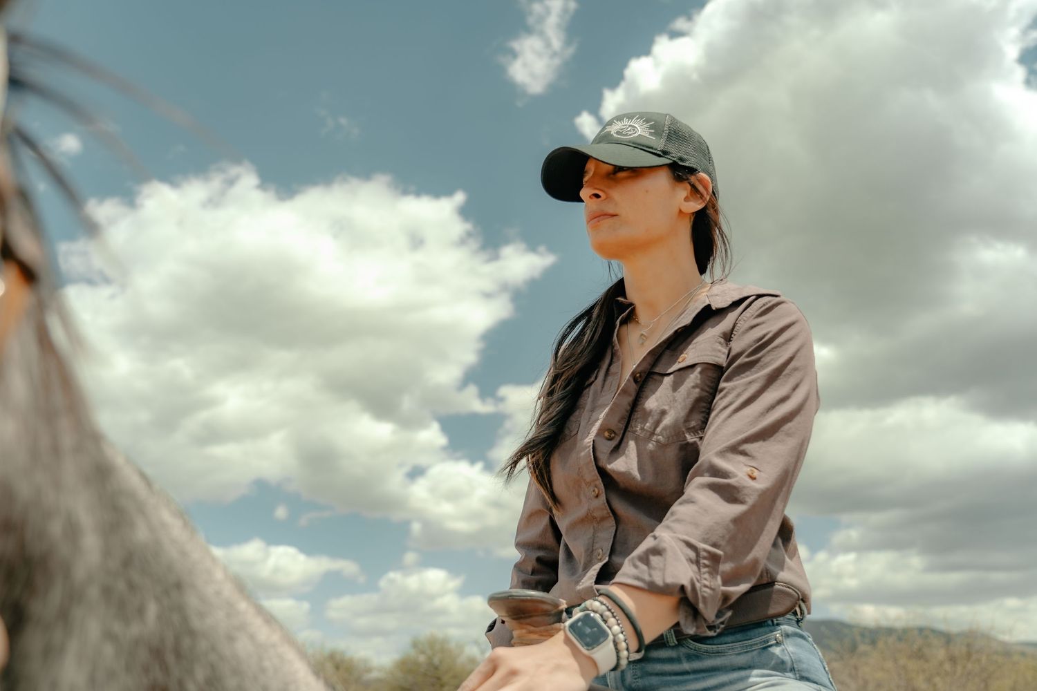 A silhouette against cloudy skies wearing a baseball cap and casual attire.