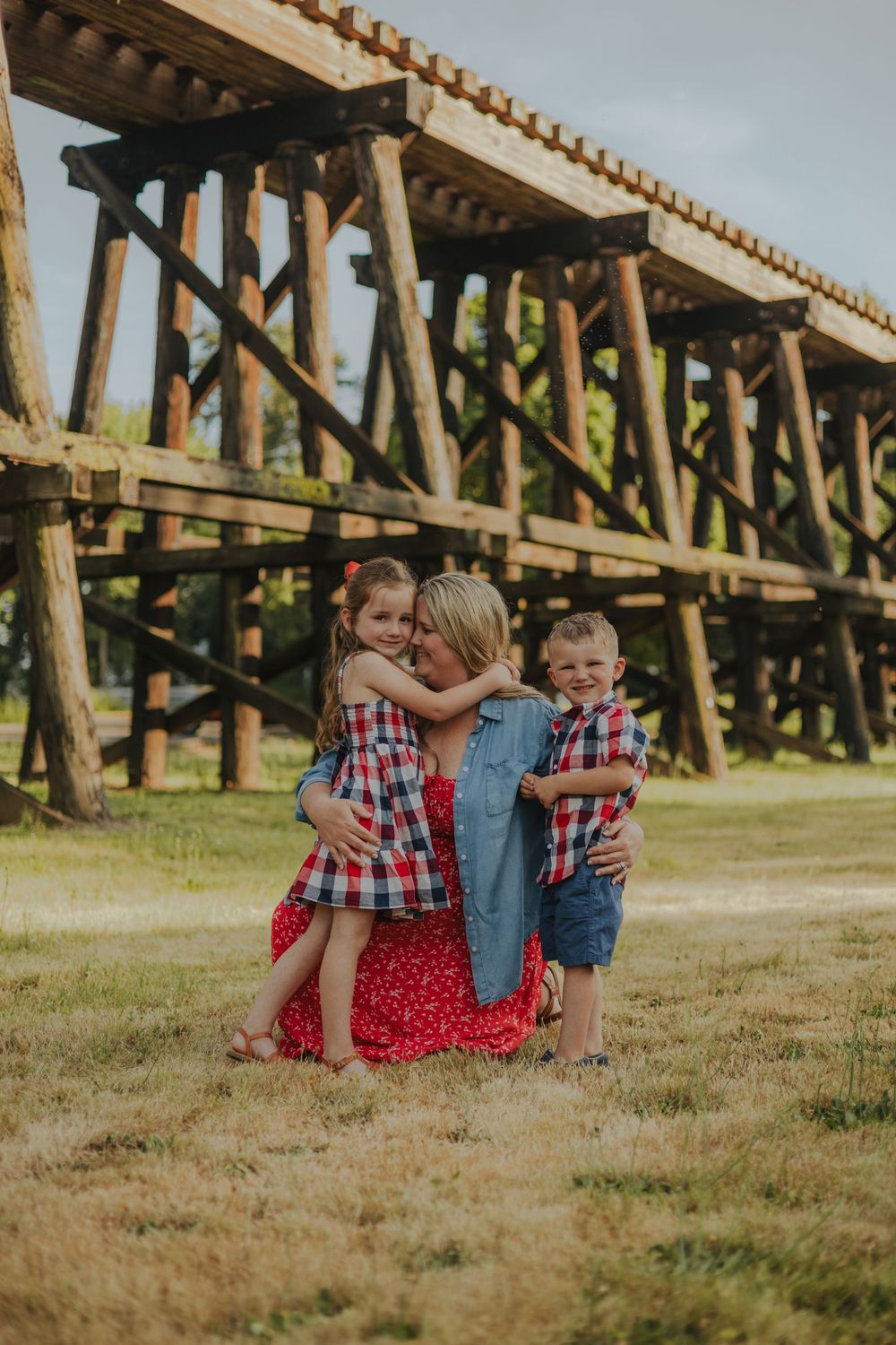 A tender family moment captured beneath a rustic wooden trestle bridge.
