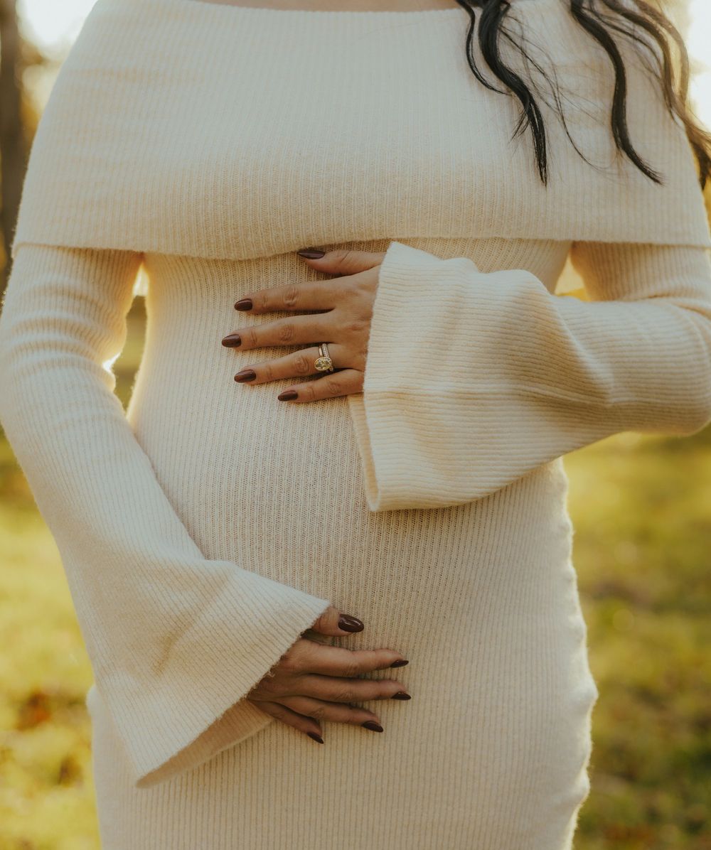 Close-up series of a pregnant belly in a white sweater showing different hand positions during pregnancy.
