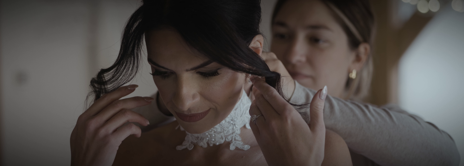 A bride in a veil being prepared for her wedding day in soft lighting.
