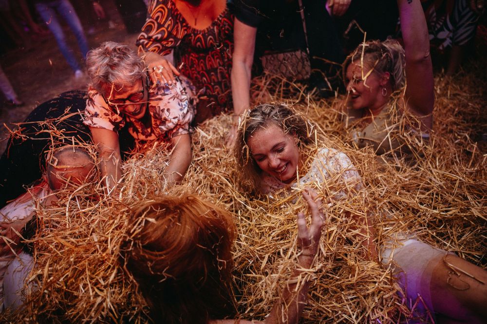De bruid en haar vriendinnen zijn bedolven onder het stro tijdens het avondfeest van hun bruiloft