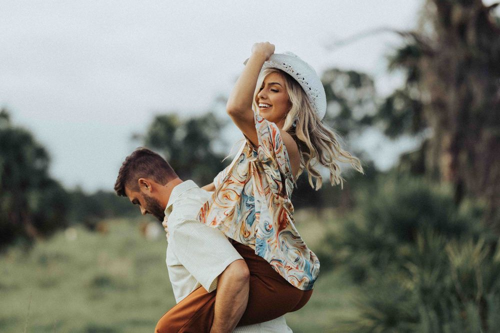 A couple enjoys a playful piggyback ride in a lush tropical setting.
