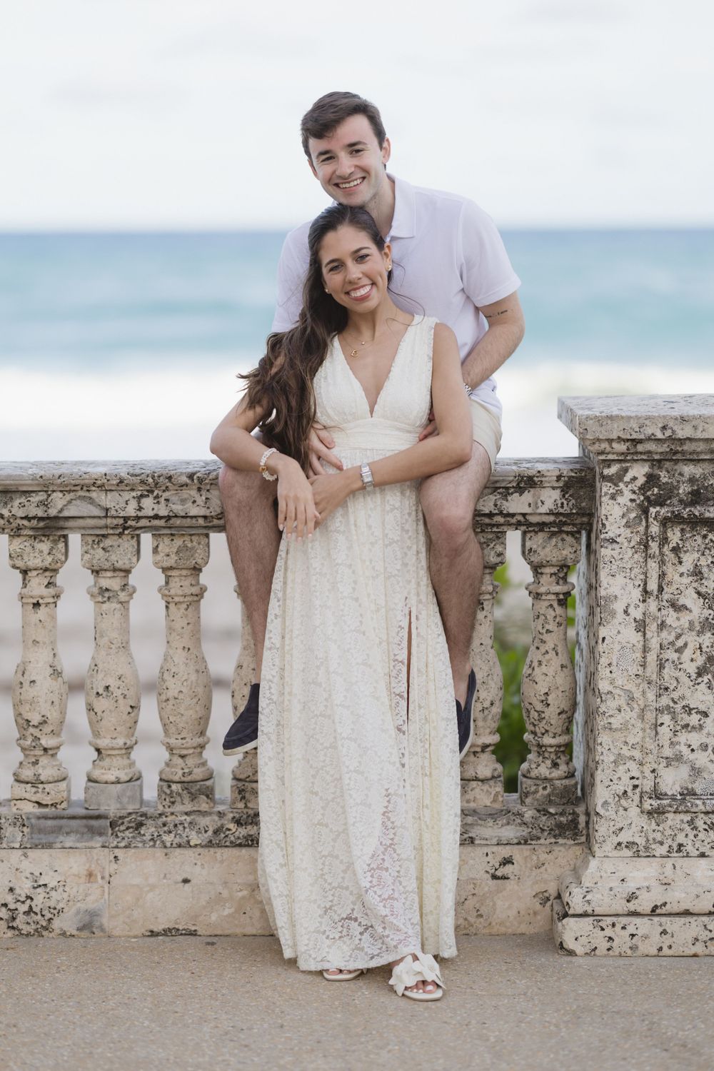 A tender moment shared on a seaside balcony with ocean waves in the background.