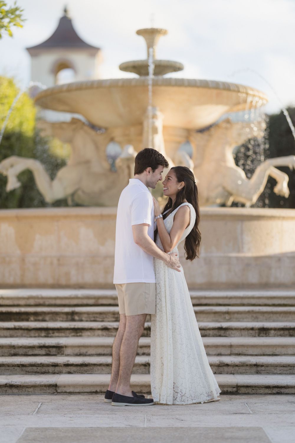 A romantic scene in front of an ornate tiered fountain with classical architecture.