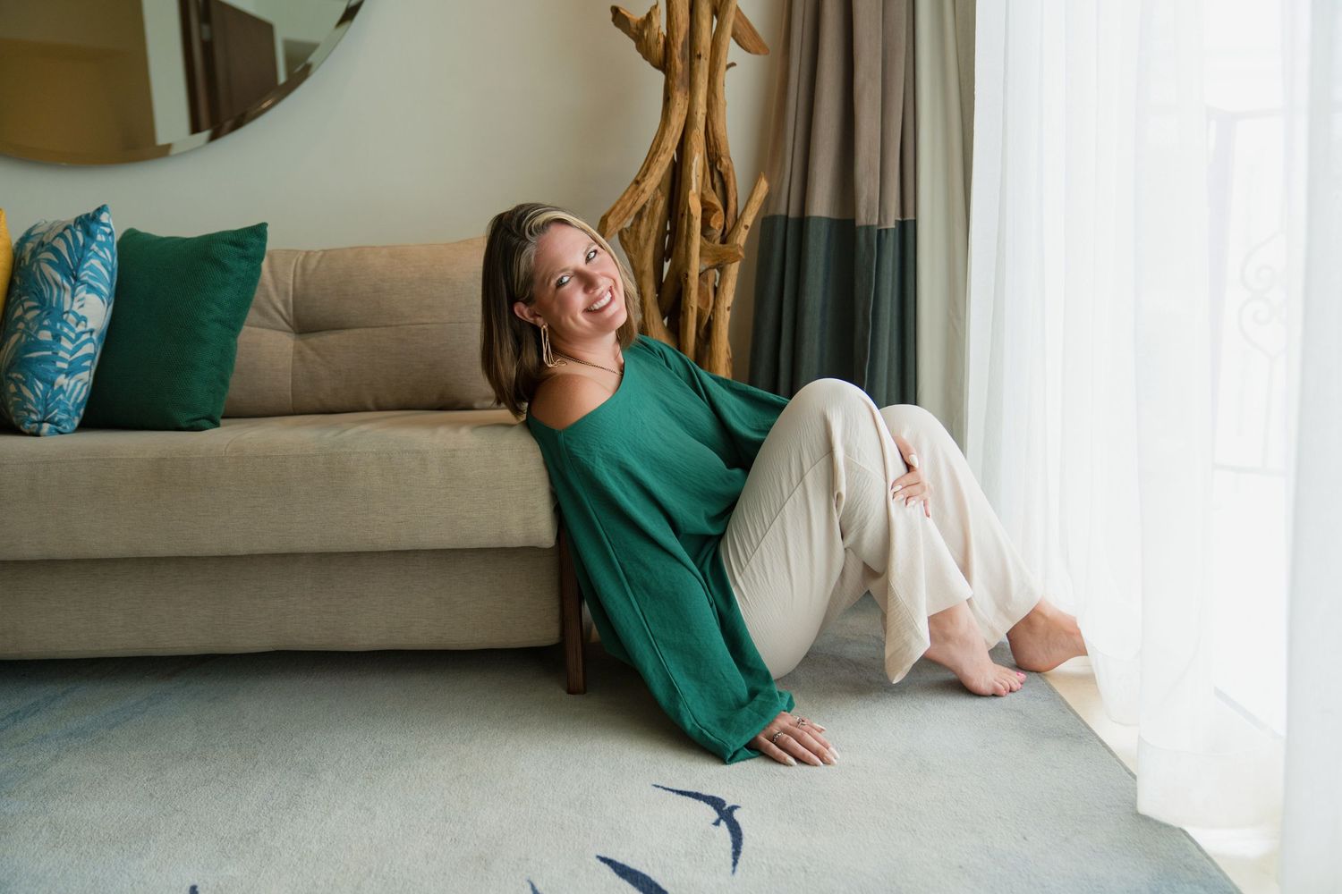 Professional portrait against turquoise backdrop featuring casual business attire and white pedestal.