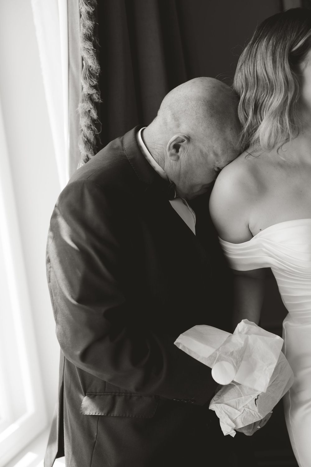 A tender moment captured in black and white as an emotional guest dabs tears with a tissue at a wedding ceremony.