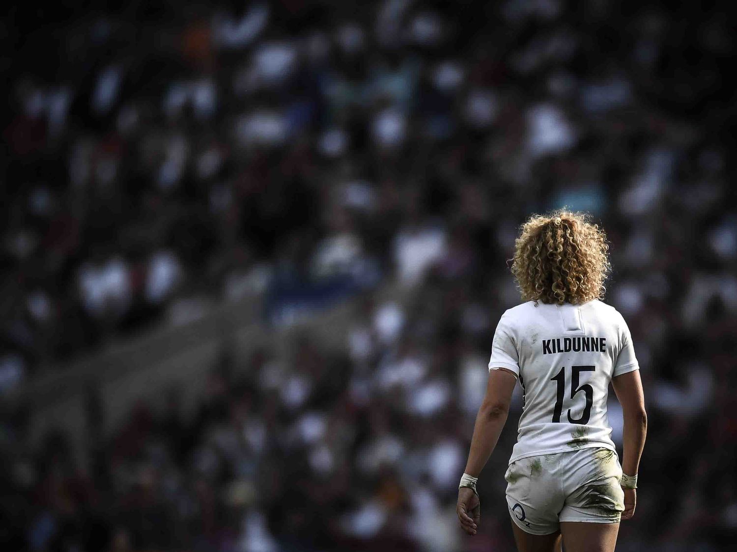 Rugby player wearing white jersey number 15 stands against blurred stadium background.