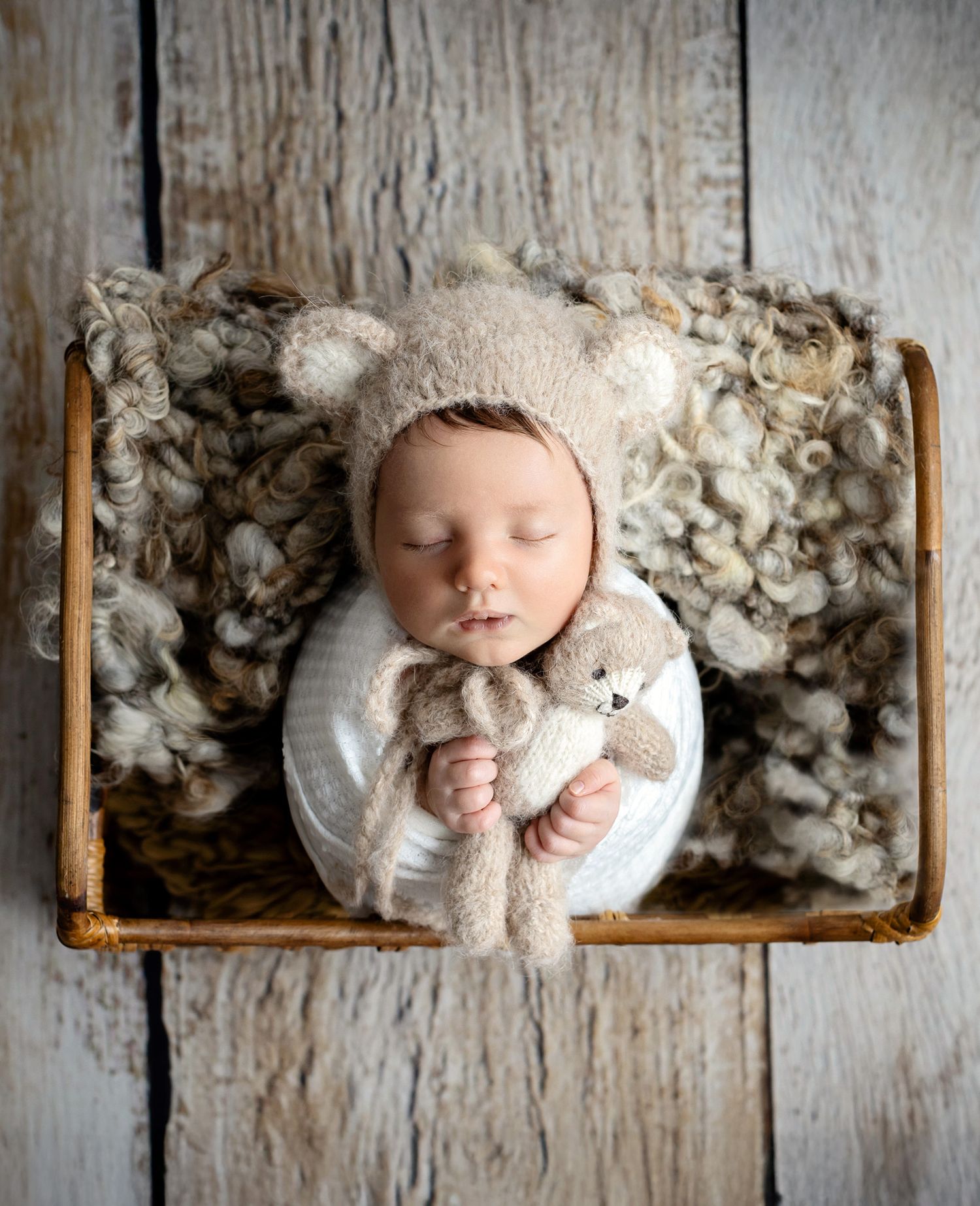 Picture of newborn baby boy with mixed neutral brown, white, stone colours wearing teddy hat and cuddling teddy in coventry.