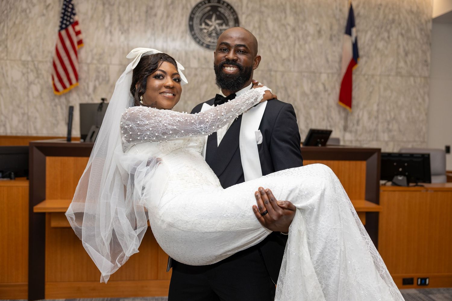 A celebratory wedding moment in a courthouse with an American flag in the background.
