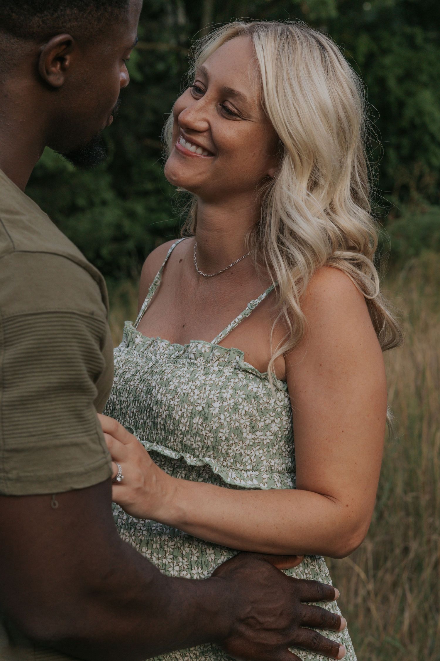 Romantic outdoor maternity portrait with couple in natural setting during golden hour.