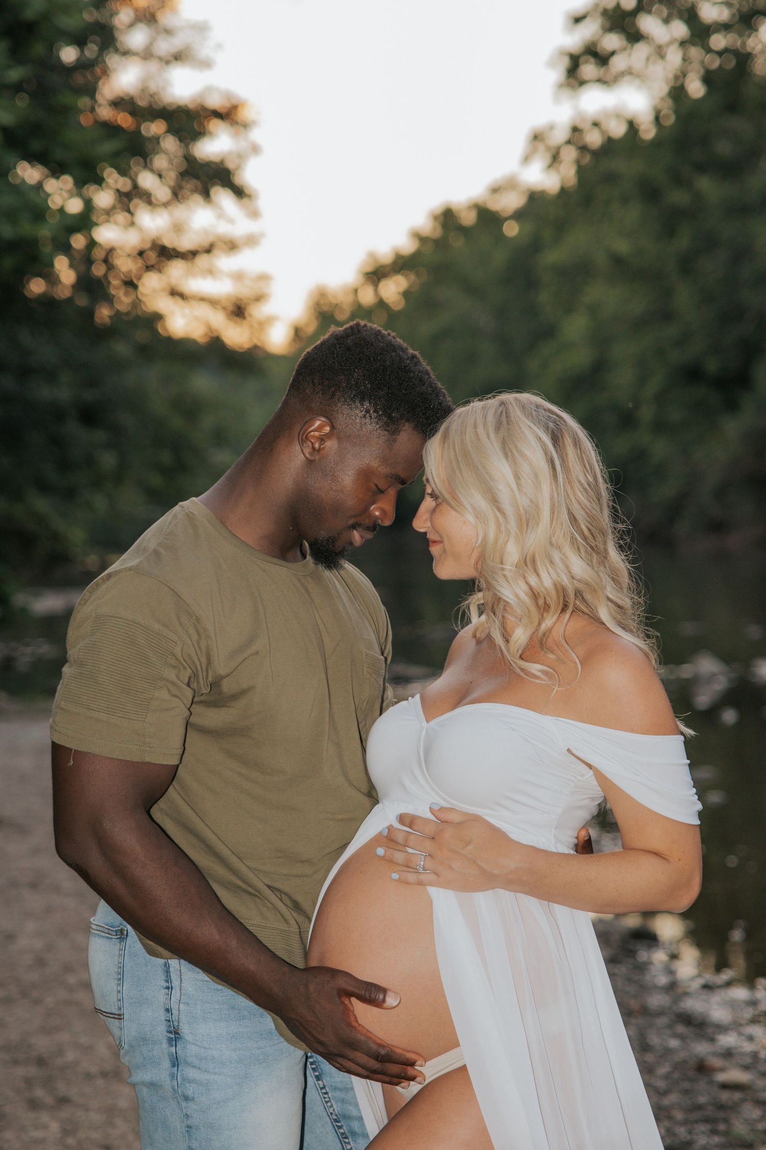 An intimate maternity photo session at sunset by a riverbank.