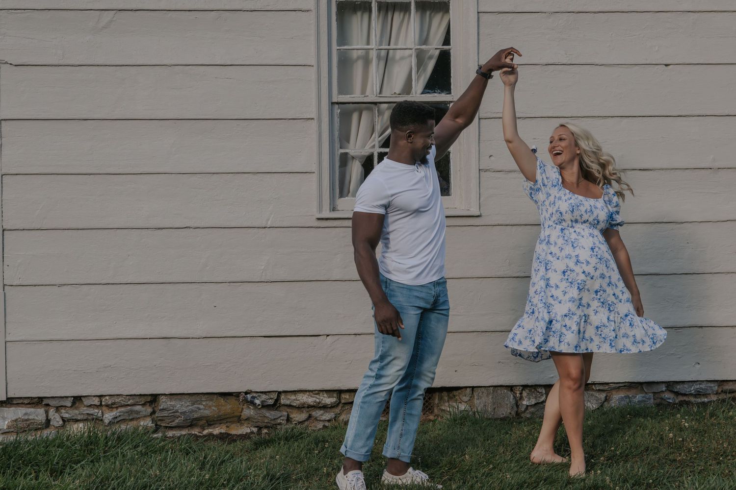 A playful outdoor dancing moment against a white building backdrop.