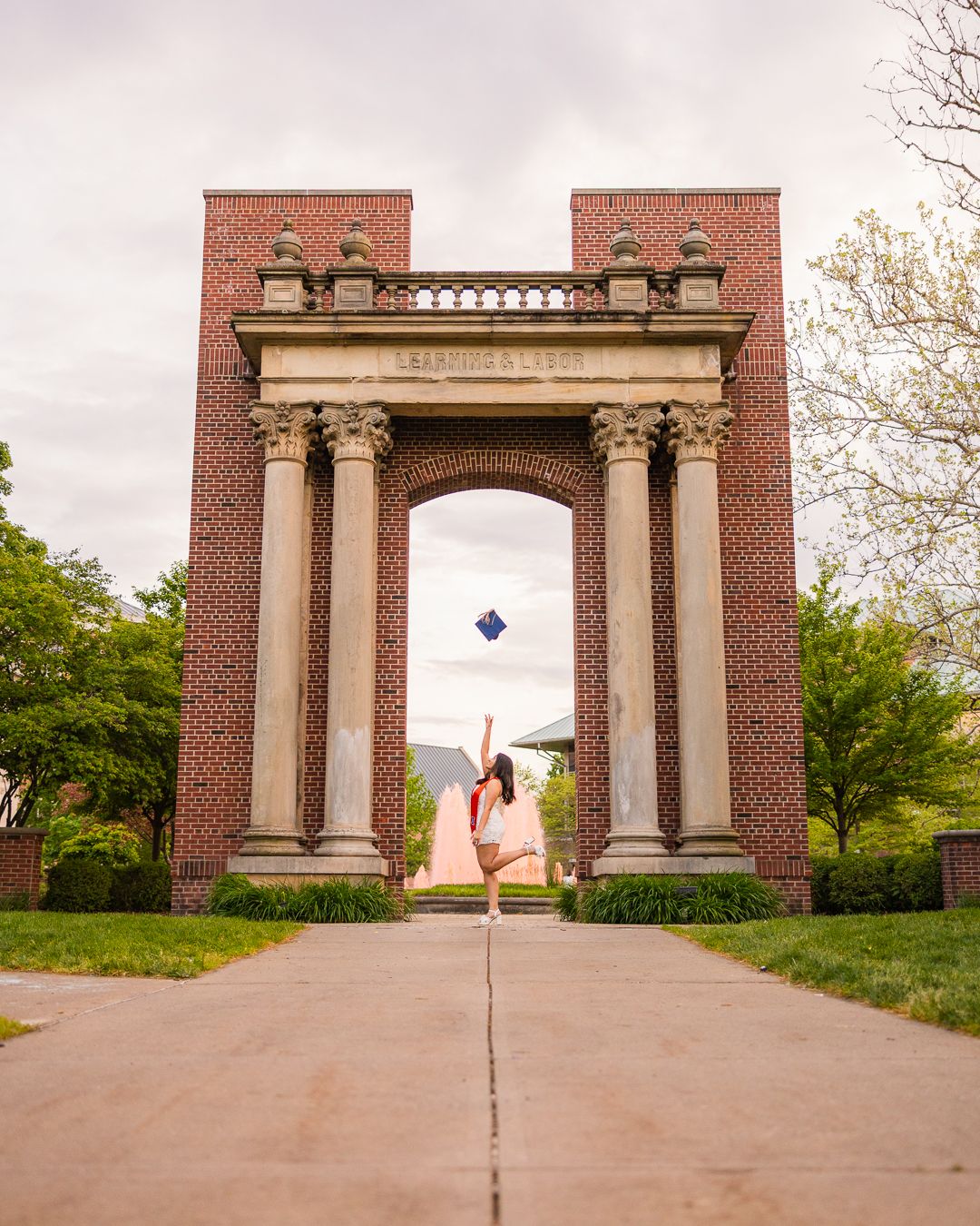 Girl tossing her cap up in the air on a cloudy day at Hallene Gateway