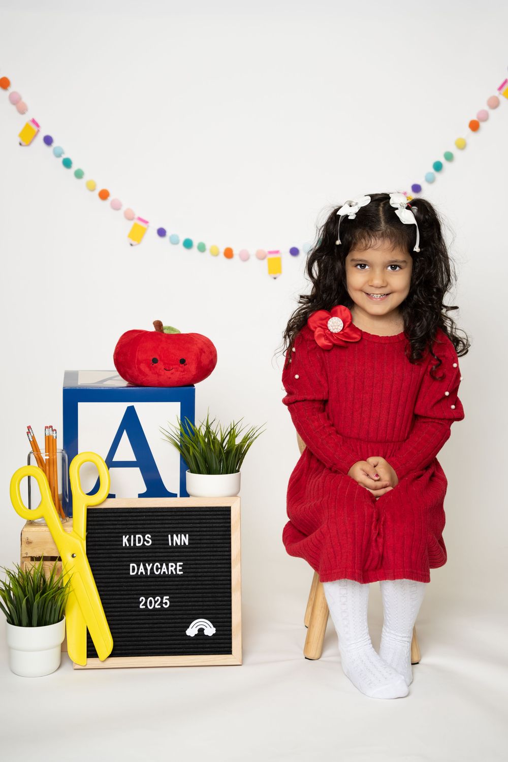 A series of photos showing a child in a red sweater with white tights against a white background with letter boards and decor.