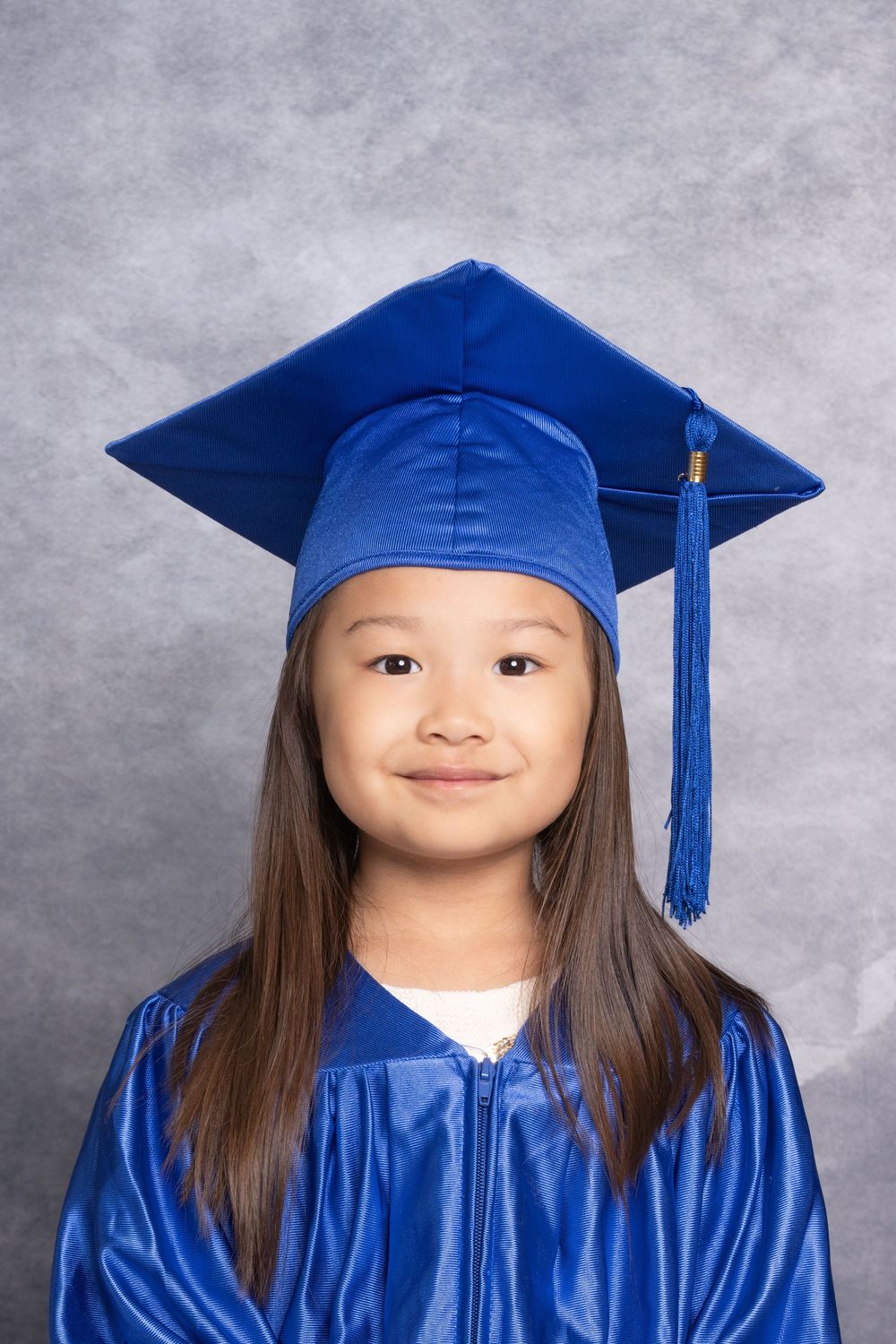 Student in blue graduation cap and gown poses for portrait series.