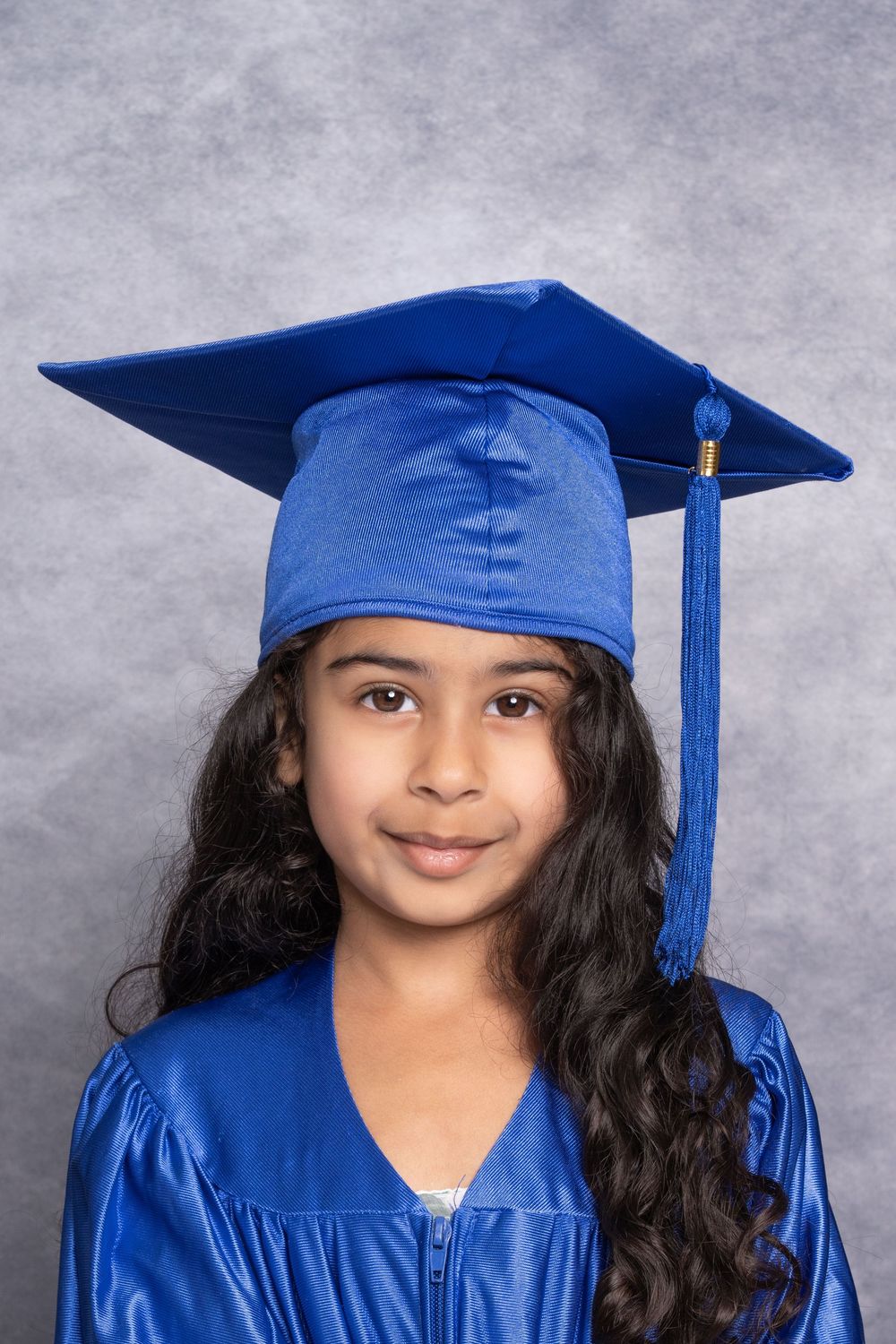 Student in blue graduation cap and gown poses for series of portraits.