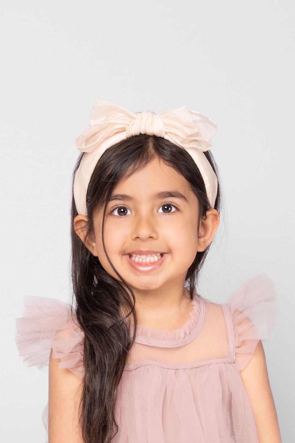 Portrait series showing expressions while wearing pink bow and dress.