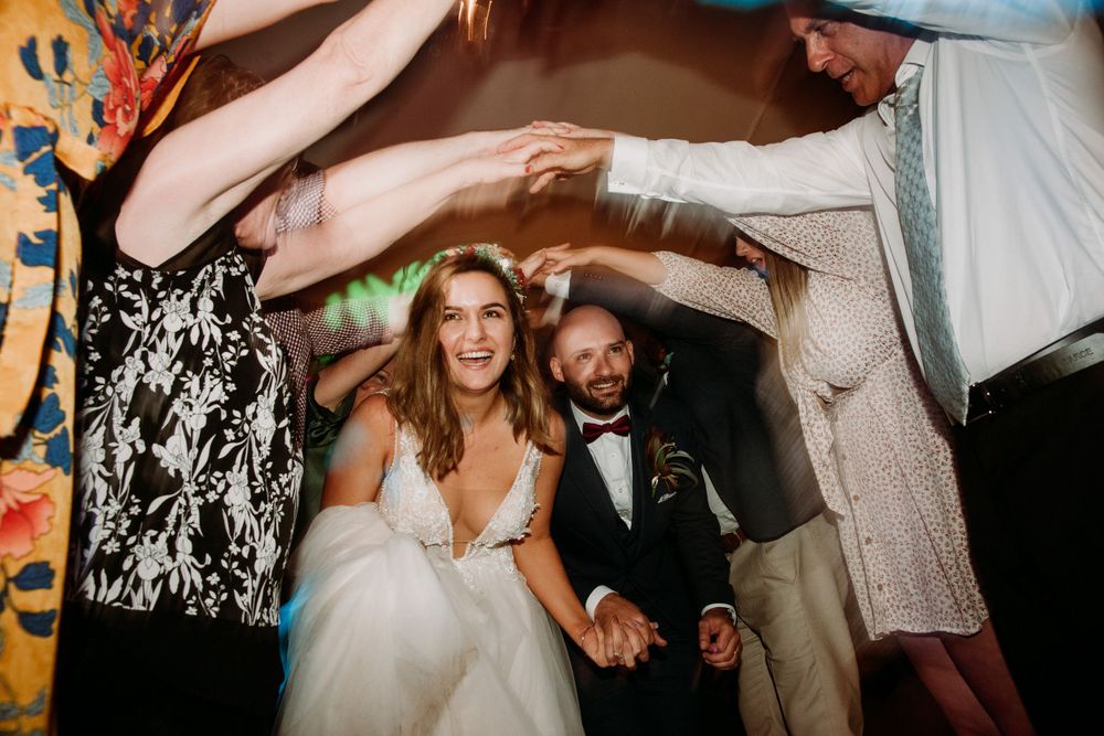 bride and groom holding hands laughing running through hand tunnel at the end of their wedding night