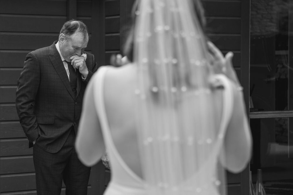 emotional father of the bride shedding a tear seeing his daughter for the first time in her wedding gown