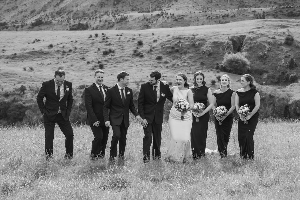 Bridal party posed and laughing in a paddock