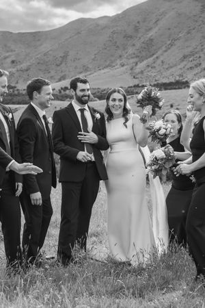Bridal party laughing and dancing in a paddock
