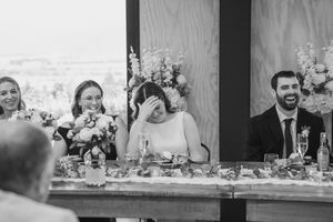 Bridal party laughing during speeches at a wedding black and white