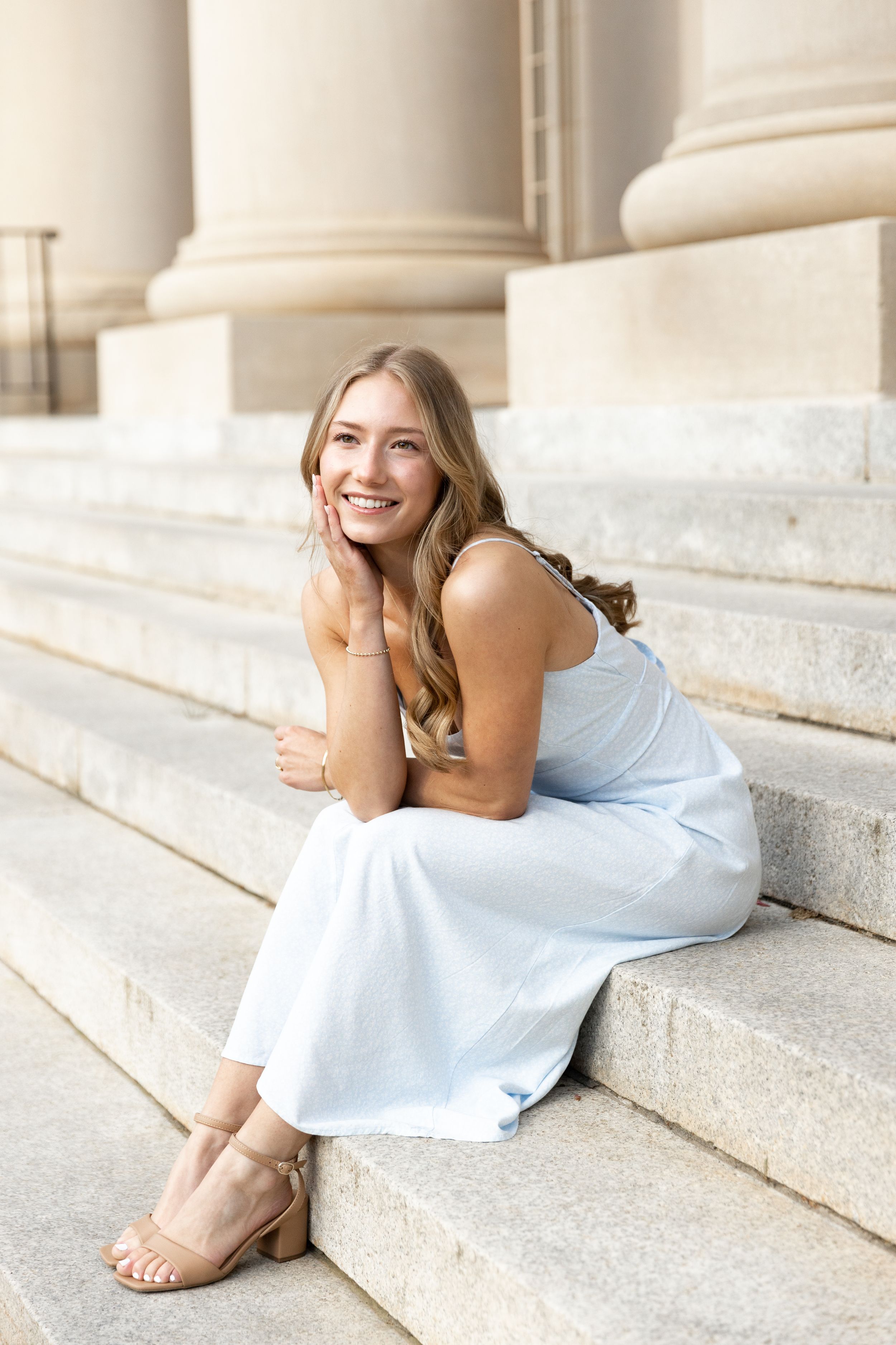 Charming senior photo of a girl on steps, wearing a dress and smiling sweetly
