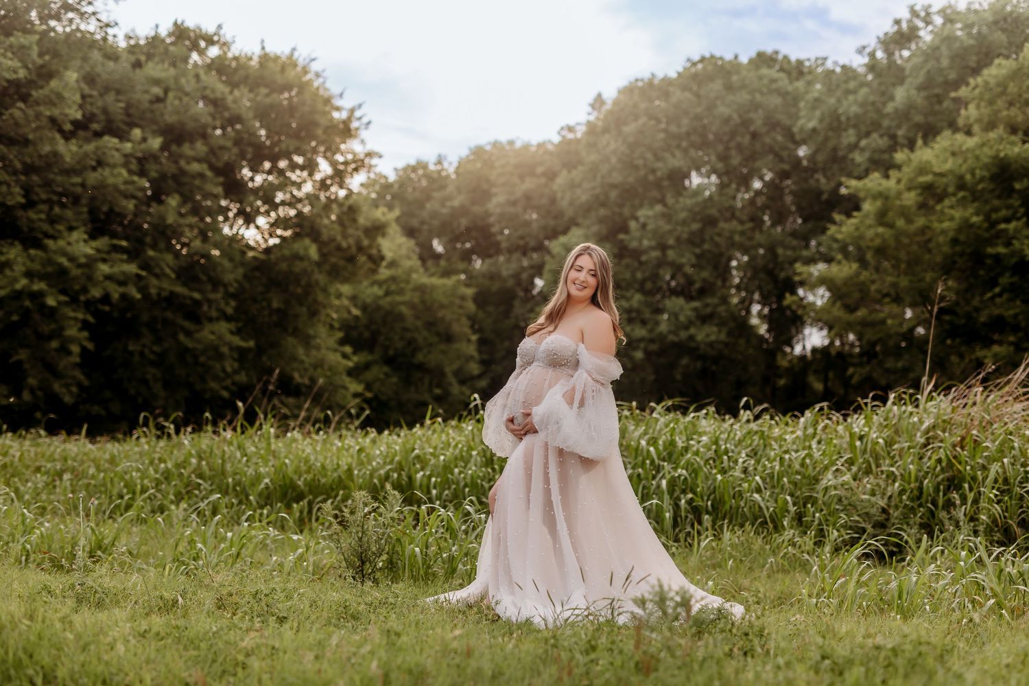 Couple sits in grassy field with two dogs during outdoor photo session.