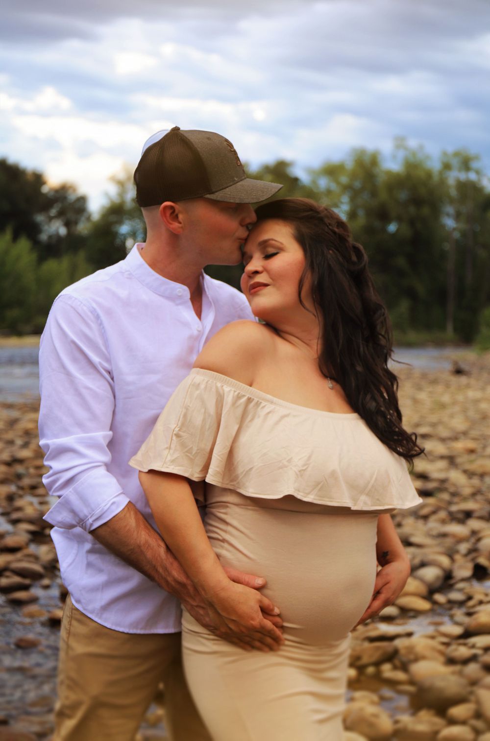 A loving couple shares an intimate moment during their riverside maternity session.