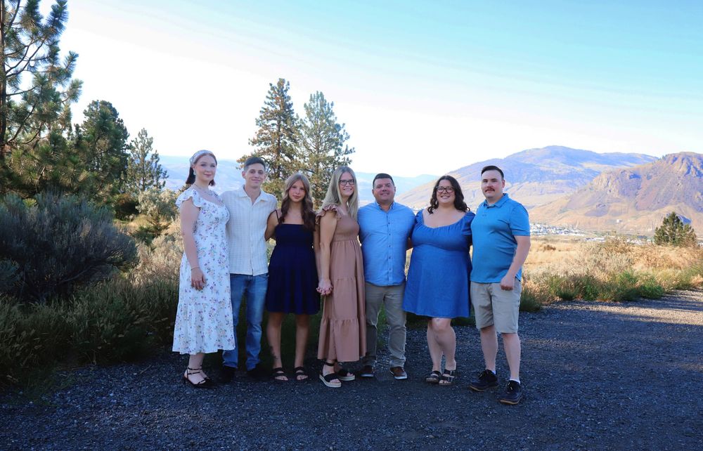 Family group photo taken on mountain overlook with scenic desert landscape in background.
