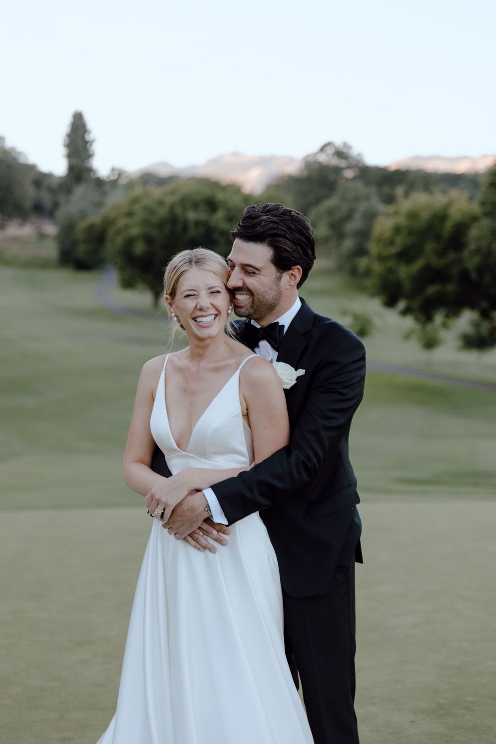 A romantic moment captured on a golf course during golden hour.