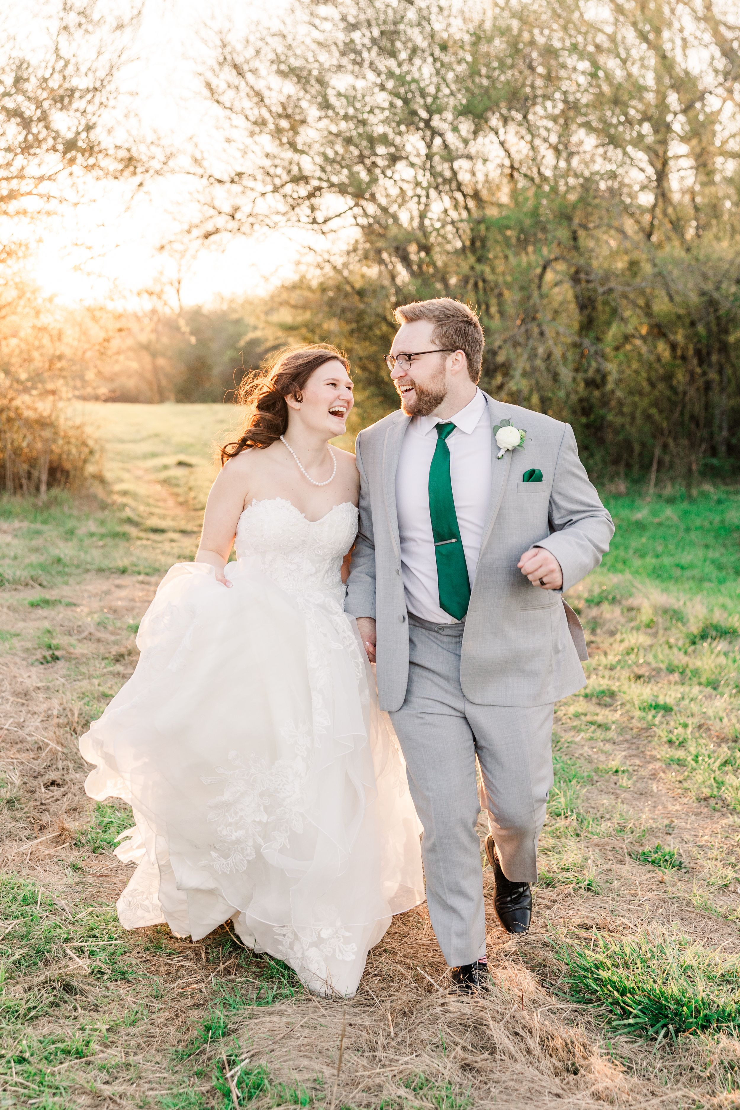 Happy couple walking together through a field at sunset.
