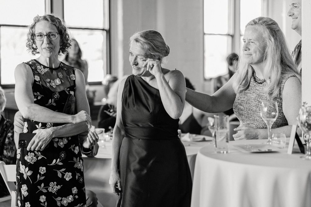Wedding guests share emotional moment at reception table.