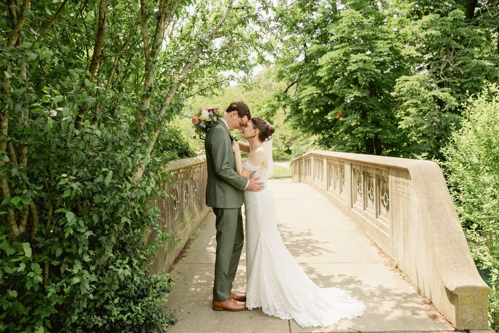 A couple in wedding attire shares a romantic moment on a scenic garden pathway surrounded by lush greenery.Cincinnati Wedding Photography