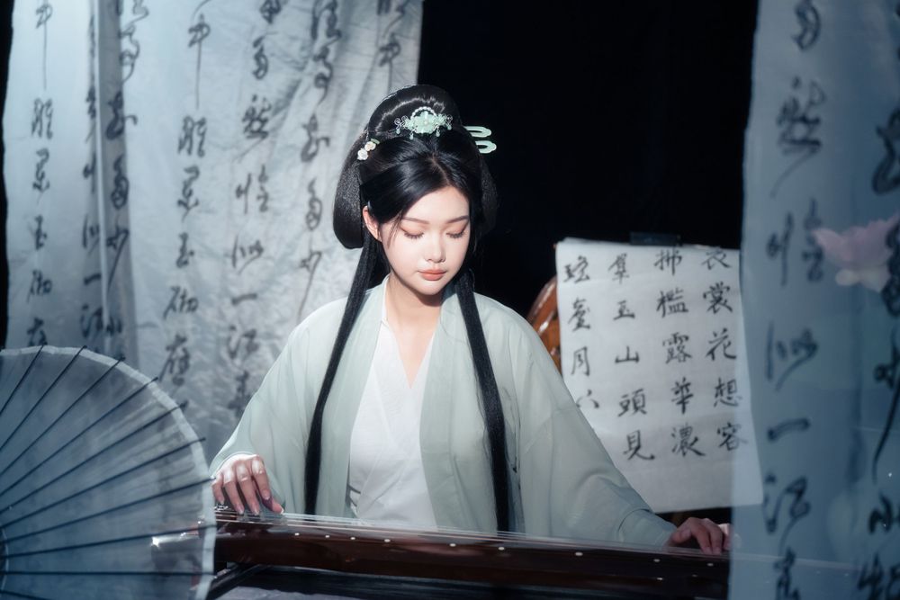 Serene and ethereal Hanfu photography of a woman playing Guqin surrounded by calligraphy scrolls, by Imagine Image Studio.