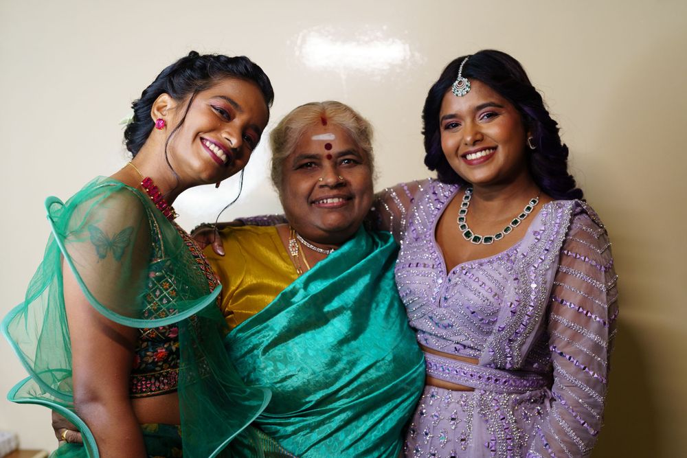 Group wearing vibrant Indian formal attire pose warmly together for a celebratory photo.