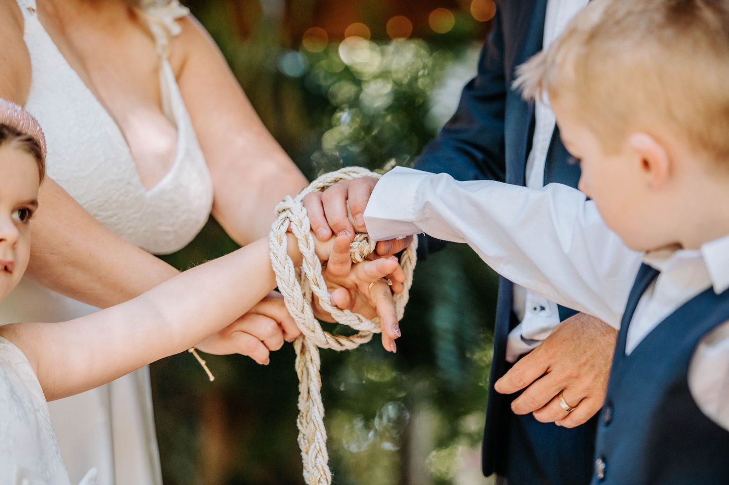 Close-up of hands participating in a unity cord ceremony during a wedding.