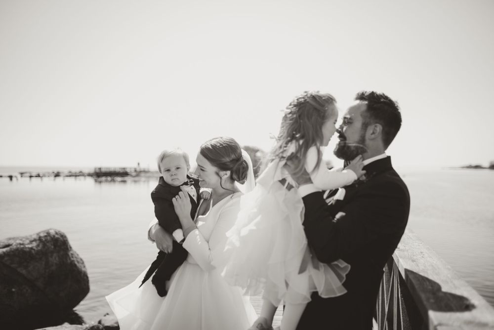 Black and white candid wedding photo of family moment on wooden dock.