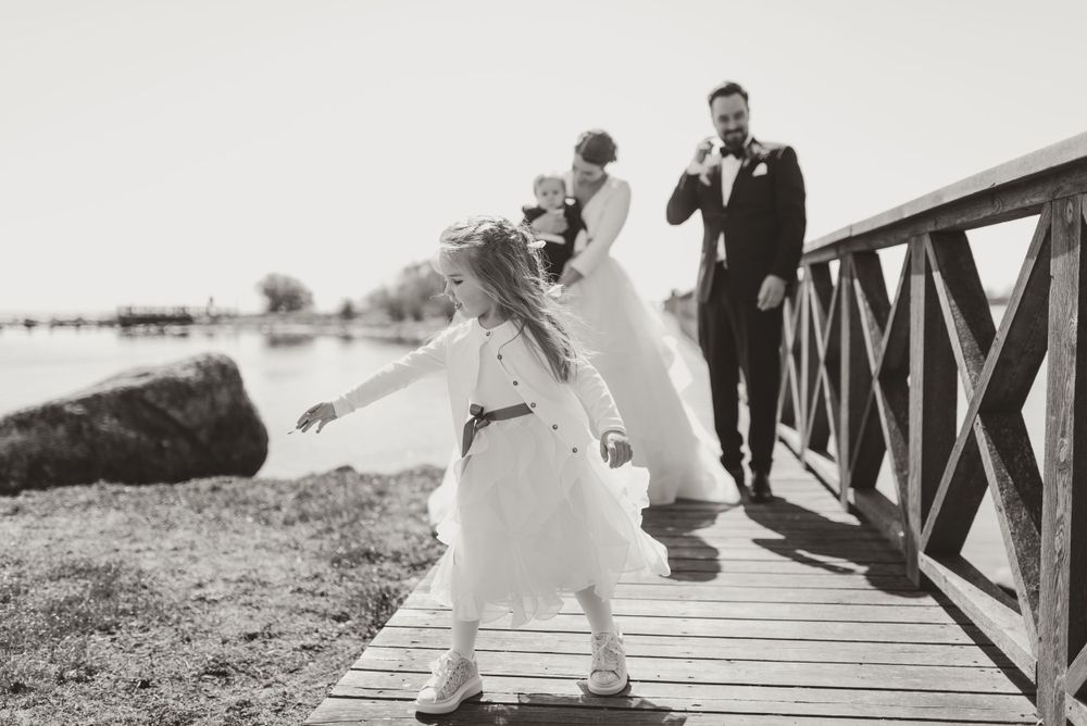 Black and white photo capturing playful wedding moment on boardwalk.