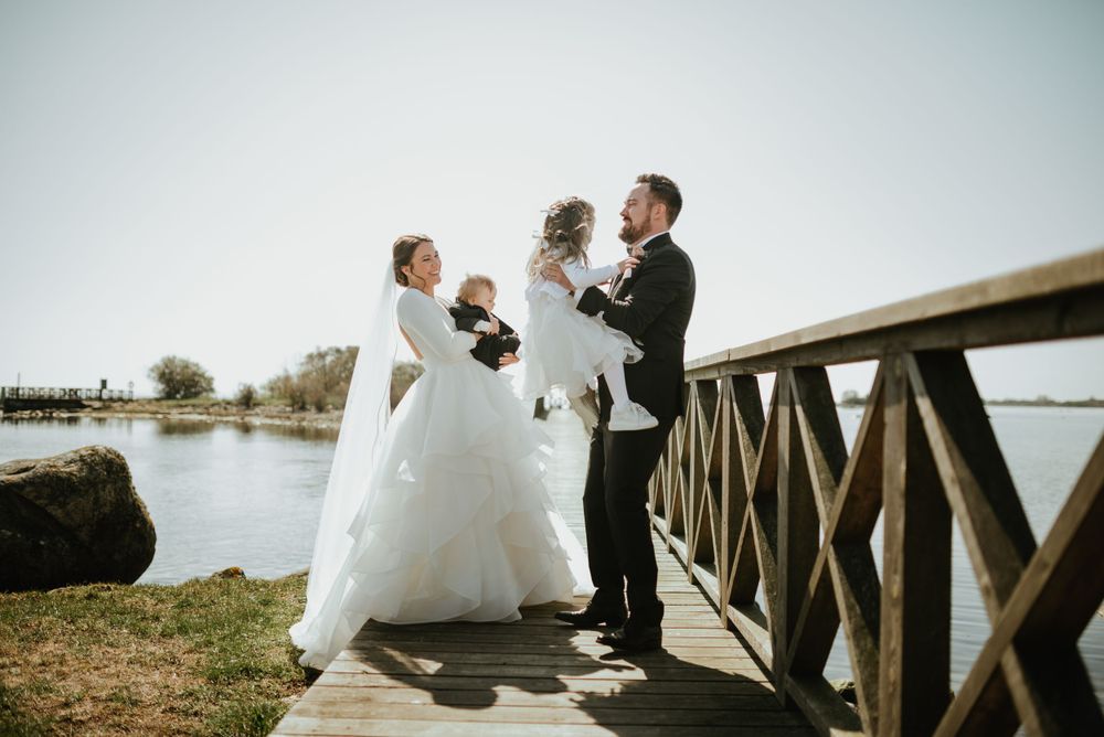 Candid wedding photo of couple interacting on wooden boardwalk by water.