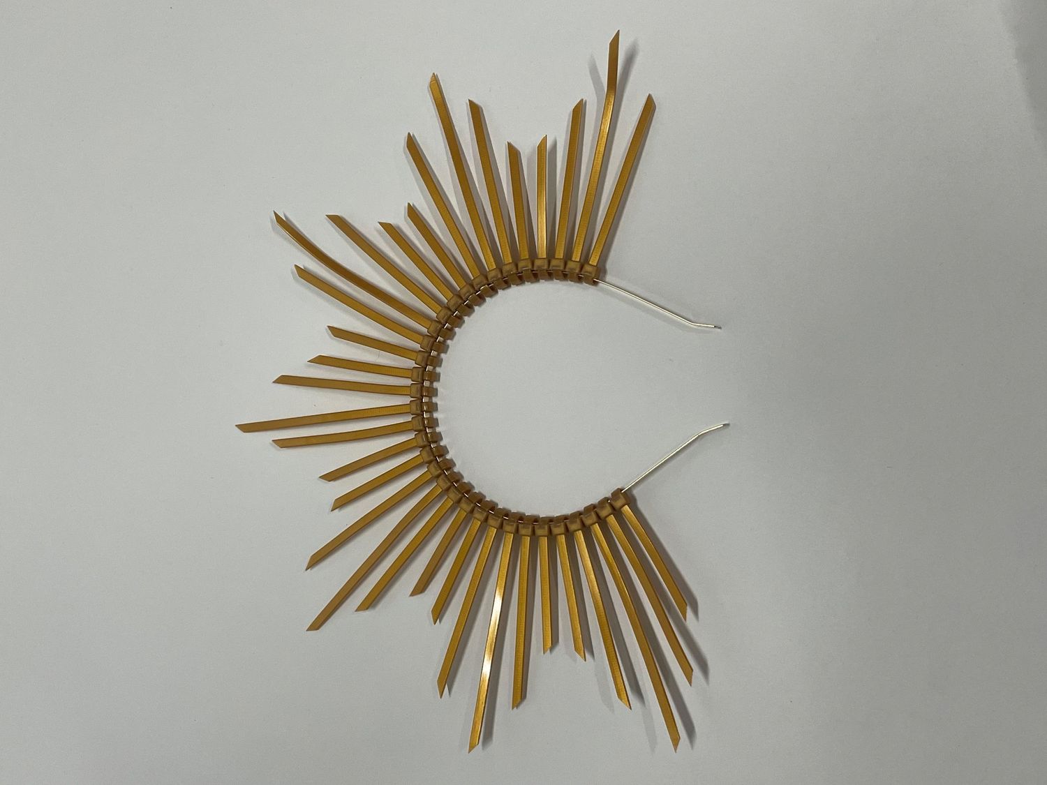 Gold sunburst crown with radiating spikes arranged in a dramatic semicircle pattern.