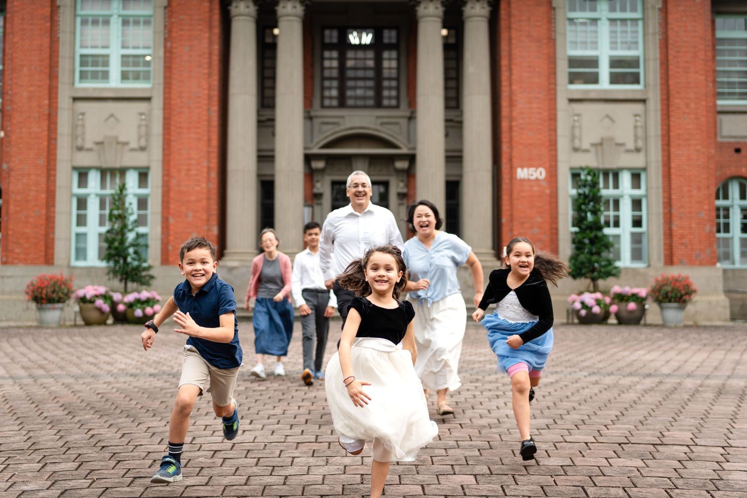 A group runs joyfully down brick steps in front of a classic red brick building.